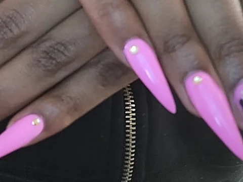Long pink stiletto nails with rhinestones and a purple marbled accent nail